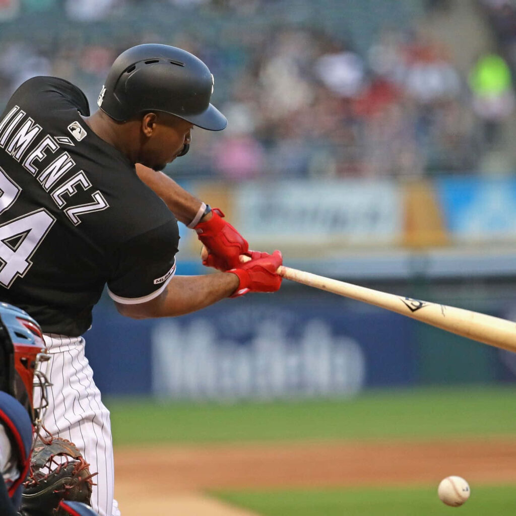 Eloy Jiménez mid-swing in dynamic baseball action with vivid team colors and blurred stadium background Wallpaper