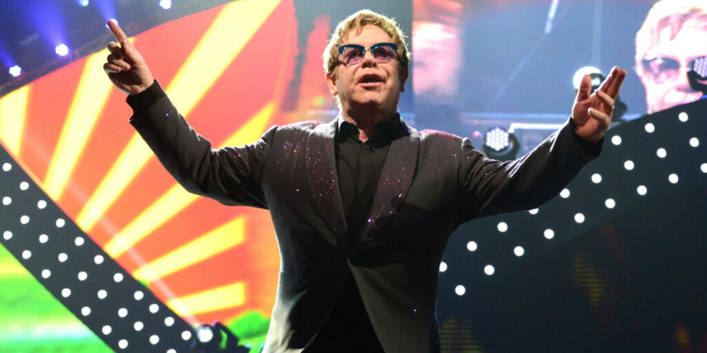 Elton John vibrant concert wallpaper with sparkling outfit colorful lights and geometric patterns