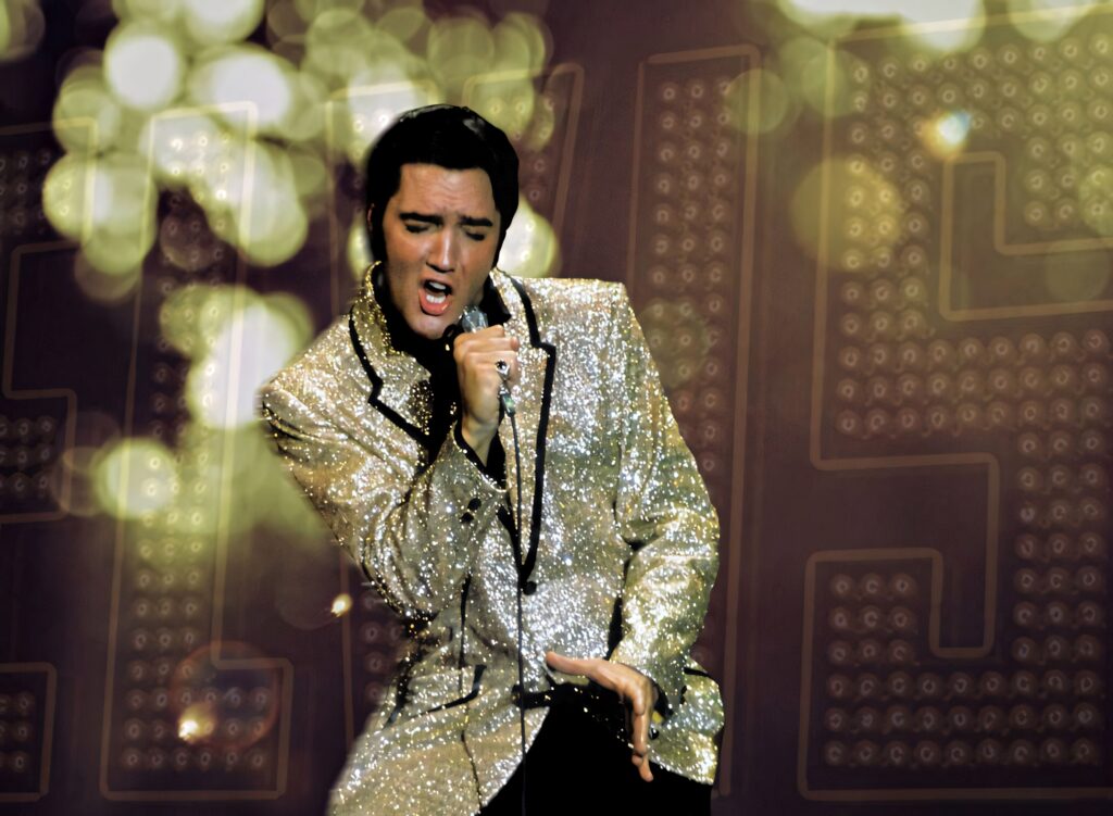 Elvis Presley performing in glittering coat with sparkling lights and golden bokeh background Wallpaper