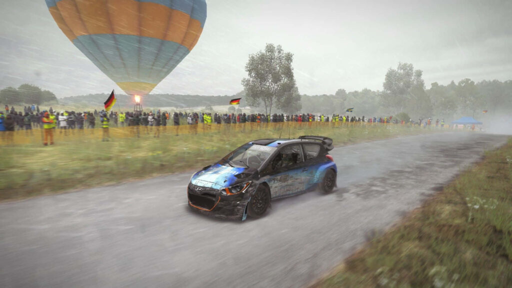 Intense Dirt Rally Race: Car Powersliding in Mud with Spectators and Hot Air Balloon - Exciting Motorsport Scene for Fans Wallpaper