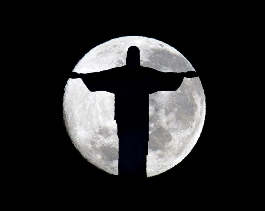 Embracing the Divine: Jesus Welcomes You with Open Arms Against a Striking Moonlit Backdrop Wallpaper
