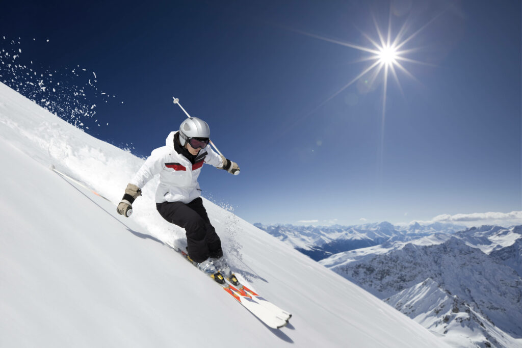 Thrilling Winter Adventures: The Majesty of Skiing on Snow-Covered Hills beneath a Luminous Blue Sky Wallpaper