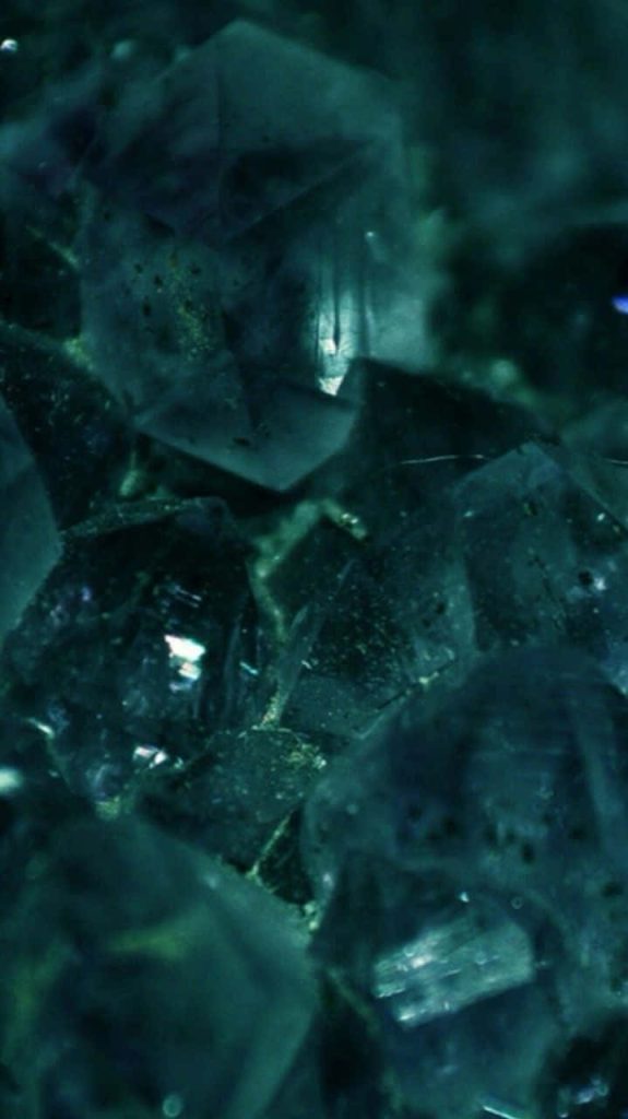 Emerald green crystalline macro wallpaper with deep teal geometric facets abstract background