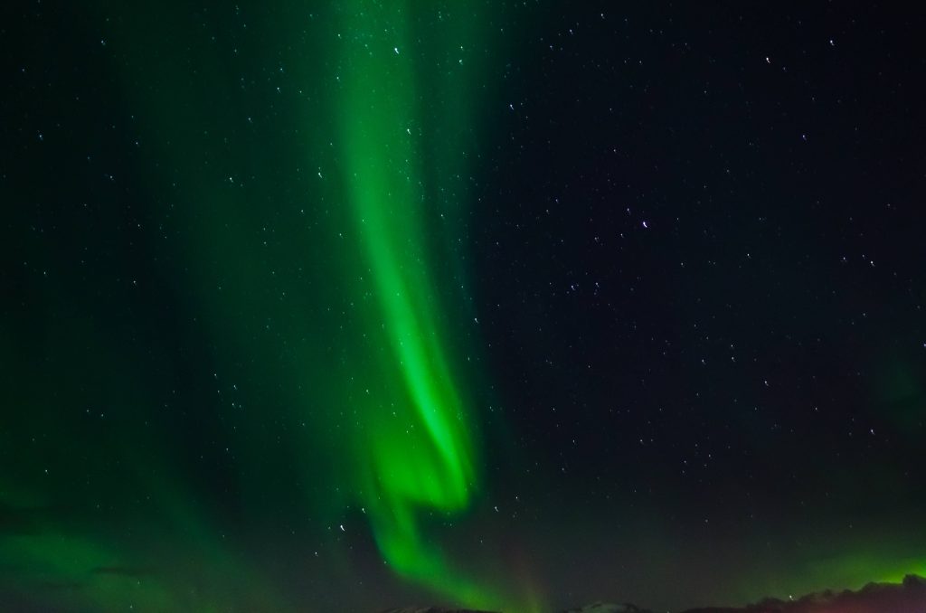 Emerald green Northern Lights dancing over starry night sky vibrant aurora wallpaper background