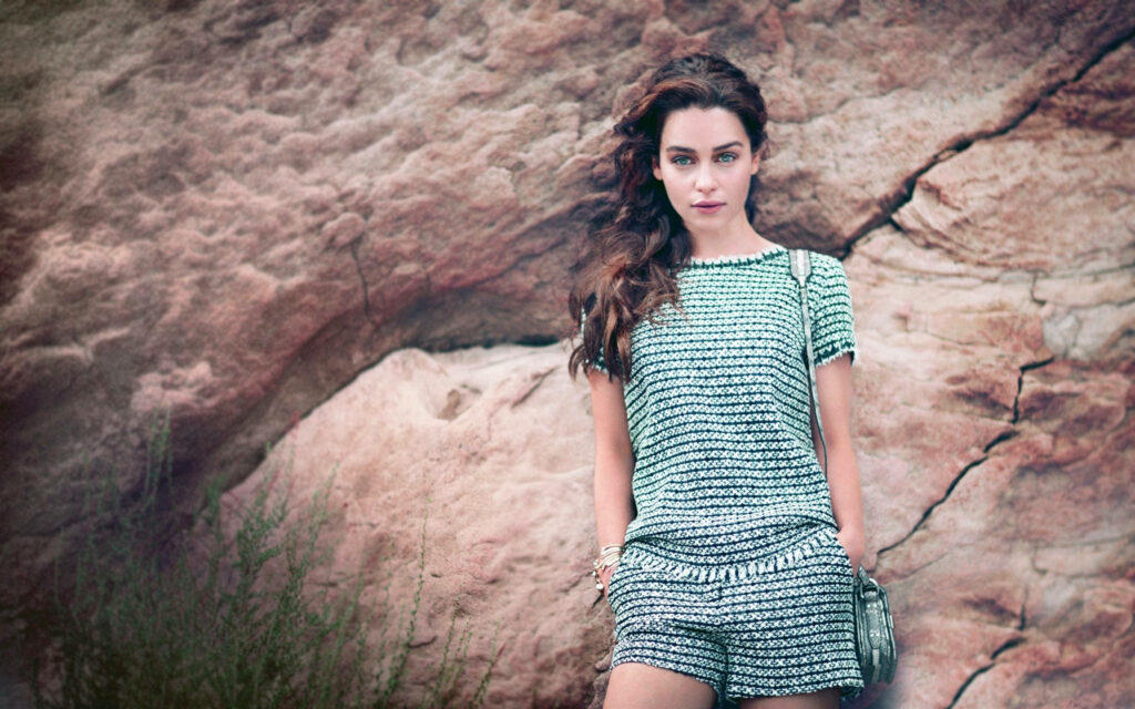 Emilia Clarke outdoor photoshoot rugged rocks stylish patterned outfit natural lighting elegance Wallpaper