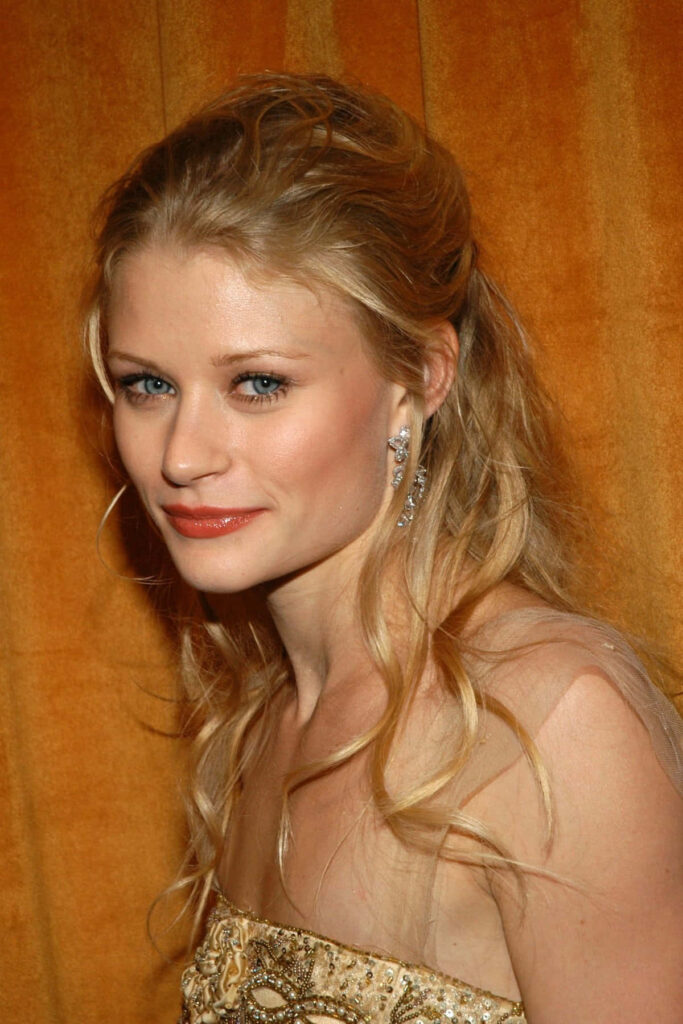 Emilie de Ravin in strapless beaded gown with tousled blonde curls against golden wallpaper