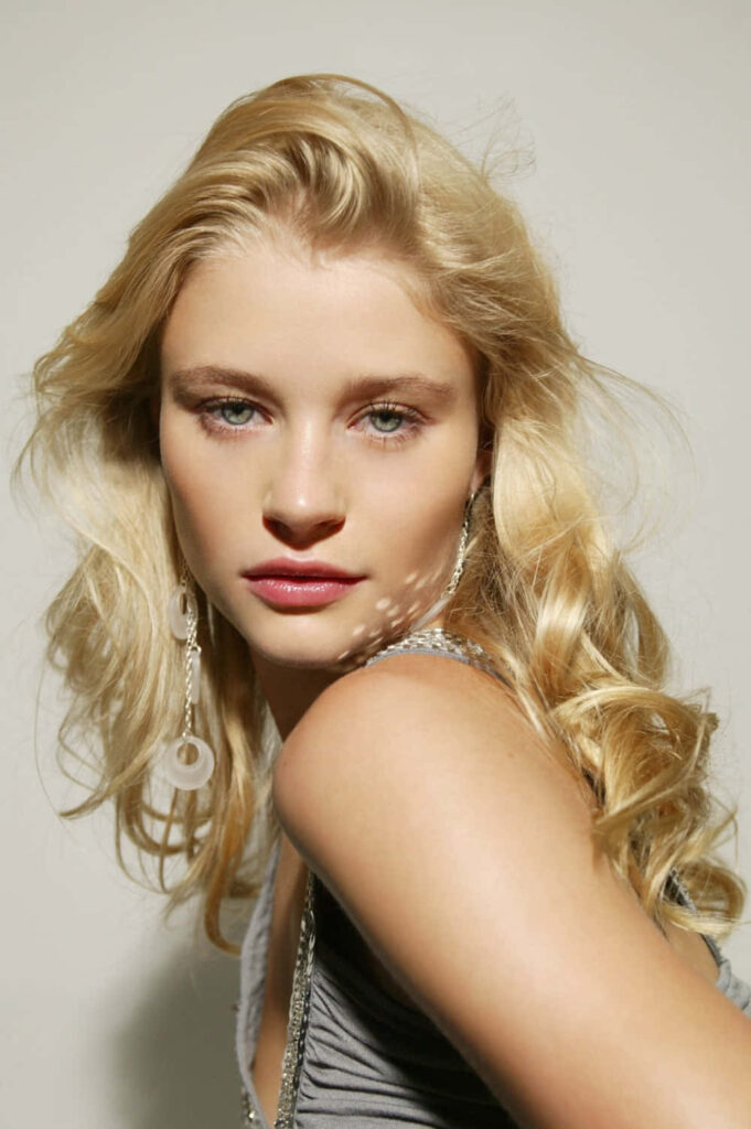 Emilie de Ravin with golden blonde hair and elegant earrings in modern portrait wallpaper background
