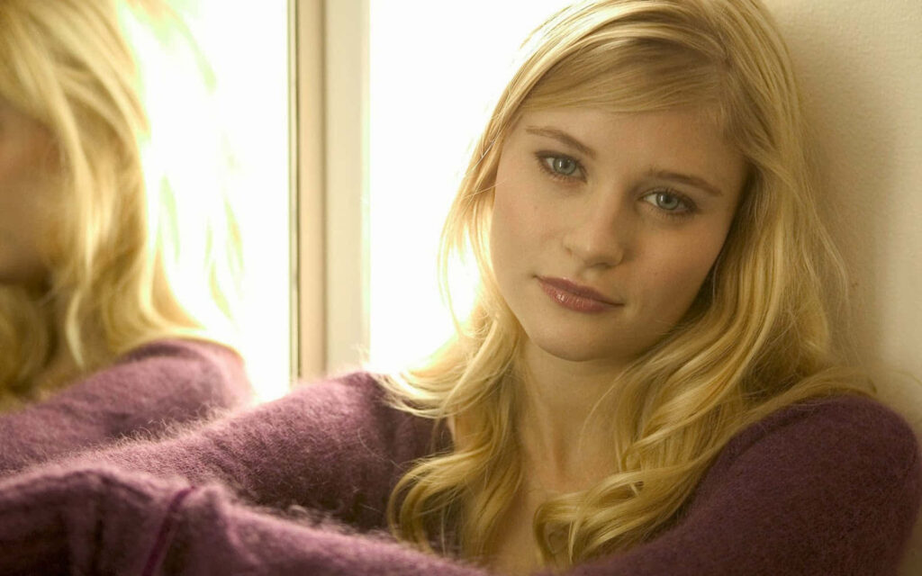Emilie de Ravin in cozy purple sweater leaning on reflective surface soft natural light wallpaper