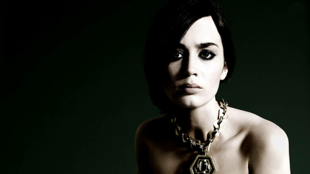 Emily Blunt intense gaze with bold necklace dramatic lighting dark background wallpaper