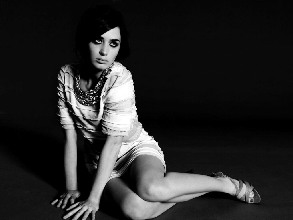 Monochrome portrait of Emily Blunt seated with dramatic lighting and deep shadows wallpaper