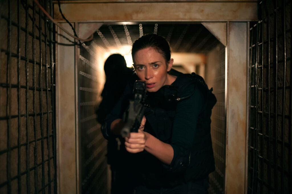Emily Blunt as Rita Vrataski aiming weapon in dim corridor intense action wallpaper background