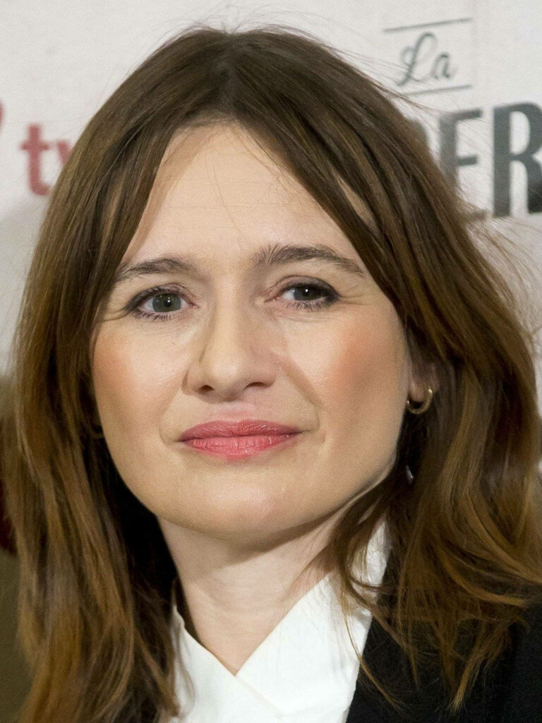 Close-up portrait of Emily Mortimer with soft lighting and blurred text background wallpaper