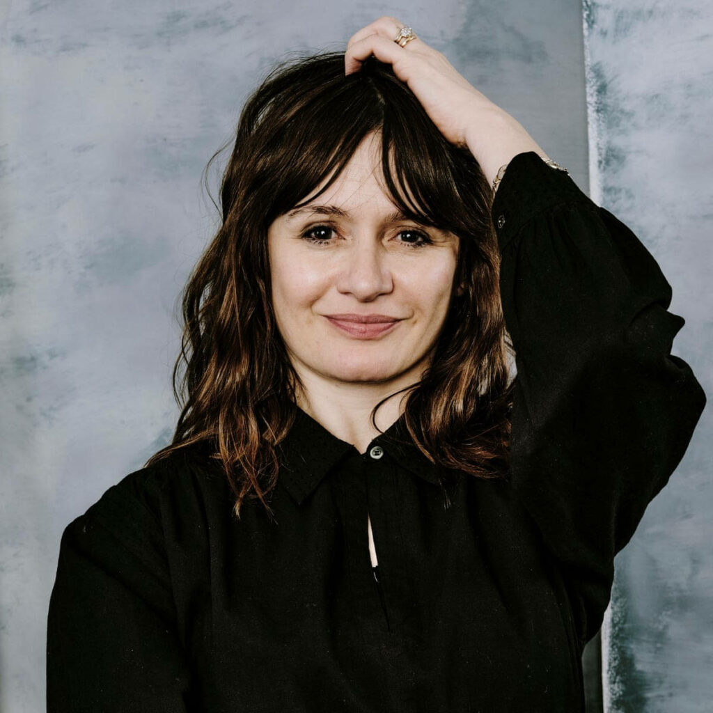 Emily Mortimer portrait wallpaper relaxed pose gentle smile soft gray background natural hair