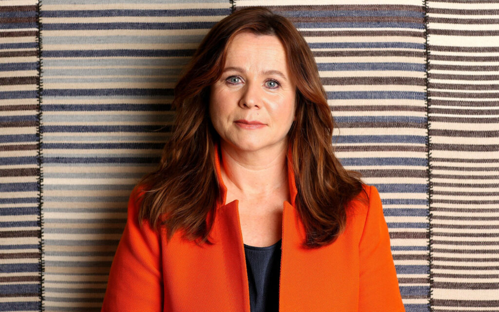 Emily Watson in vibrant red outfit against textured striped background warm portrait wallpaper