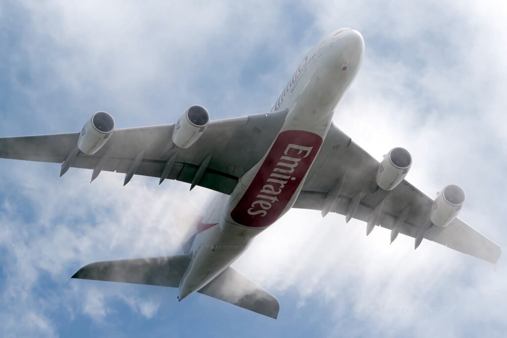 Emirates A380 flying high in partly cloudy sky showcasing massive scale and sleek design Wallpaper