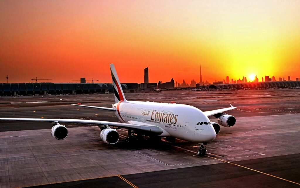 Emirates A380 on runway at vibrant sunset with Dubai skyline glowing in golden orange hues Wallpaper