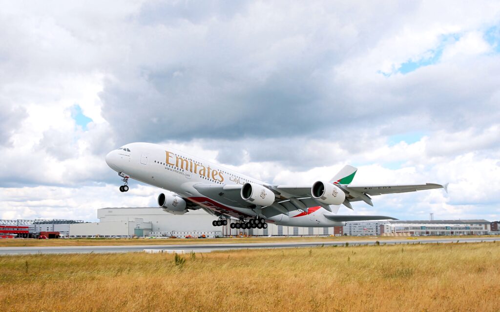 Emirates Airbus A380 mid-takeoff with dramatic clouds and modern airport backdrop wallpaper