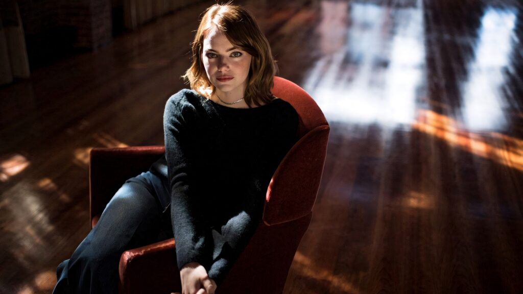 Emma Stone in red armchair with dramatic natural light on polished wood floor stylish portrait Wallpaper