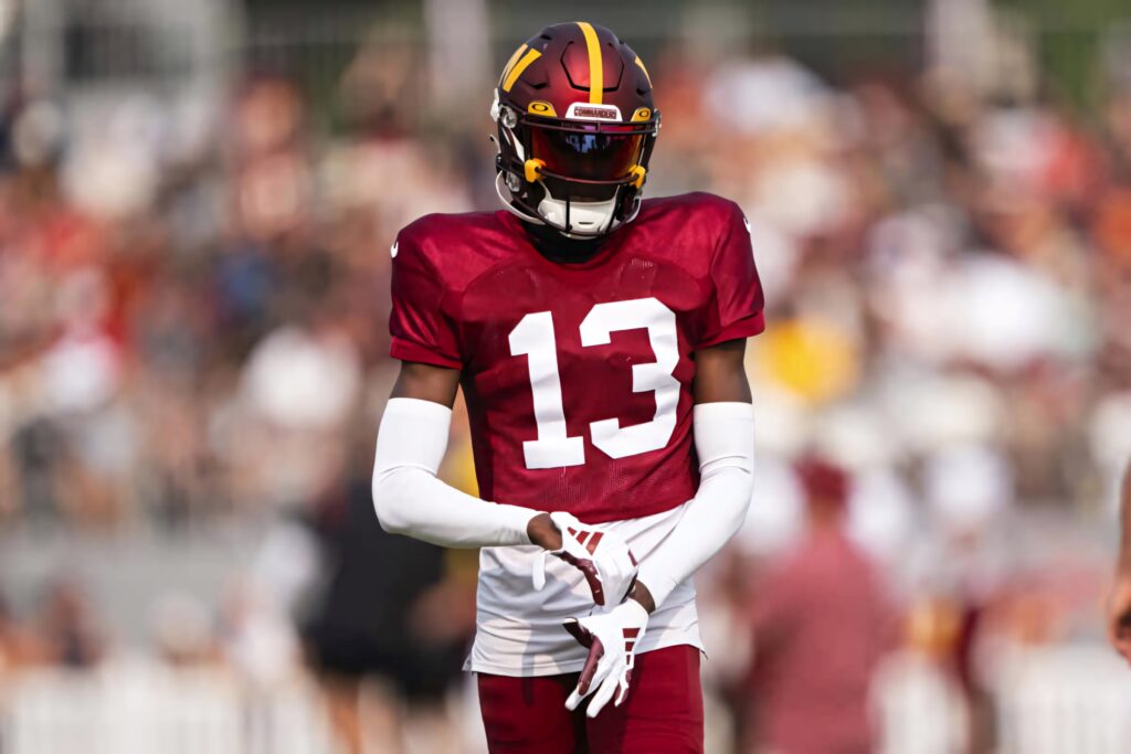 Emmanuel Forbes Jr in maroon gold football uniform number 13 focused before game stadium background Wallpaper