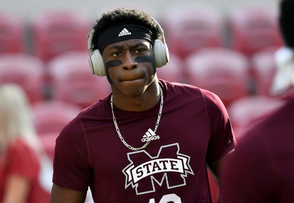 Emmanuel Forbes Jr focused in maroon Mississippi State shirt warming up with headphones in stadium Wallpaper