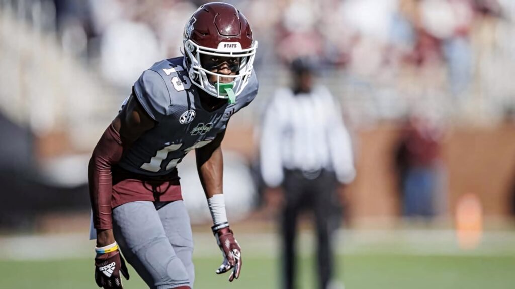 Emmanuel Forbes Jr in maroon gray uniform focused poised for next play on vibrant football field Wallpaper