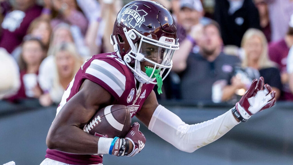 Emmanuel Forbes Jr in maroon Mississippi State uniform making dynamic football play in stadium Wallpaper
