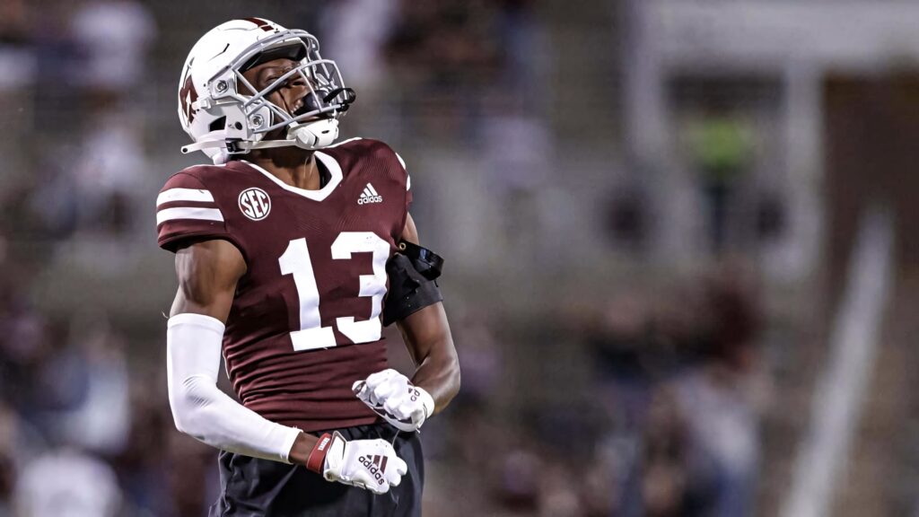 Emmanuel Forbes Jr in number 13 maroon white uniform celebrating on football field vibrant stadium background Wallpaper
