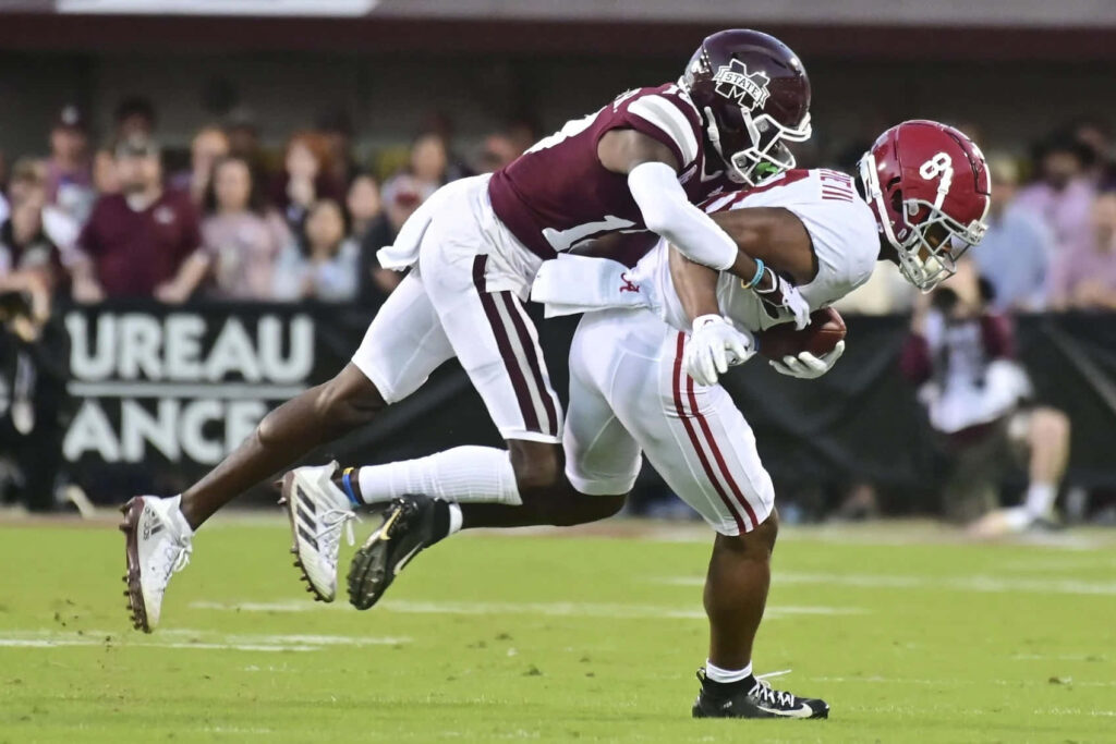 Emmanuel Forbes Jr powerful tackle in intense college football game with maroon white uniforms Wallpaper
