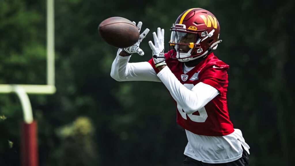 Emmanuel Forbes Jr in red jersey catching football mid-air during intense outdoor practice session Wallpaper