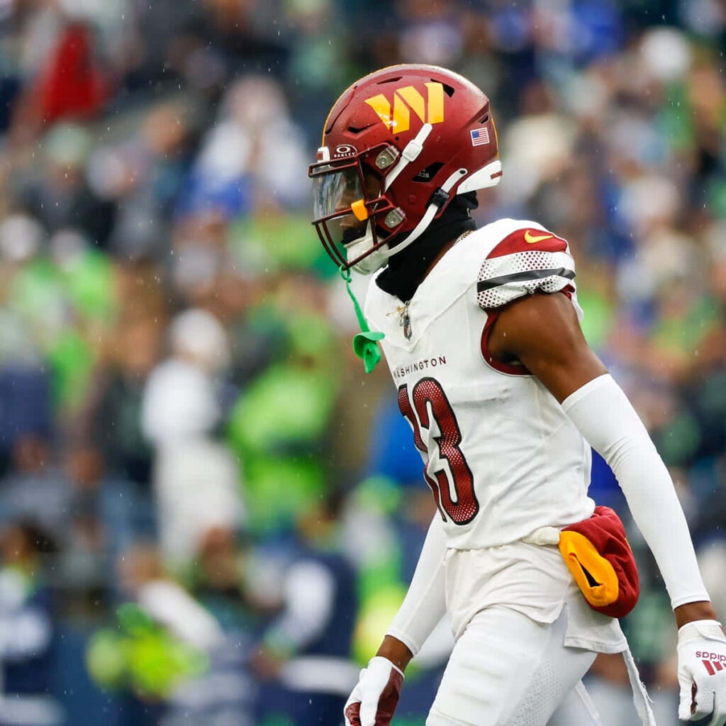 Emmanuel Forbes Jr in Washington uniform focused on football field with blurred stadium crowd background Wallpaper