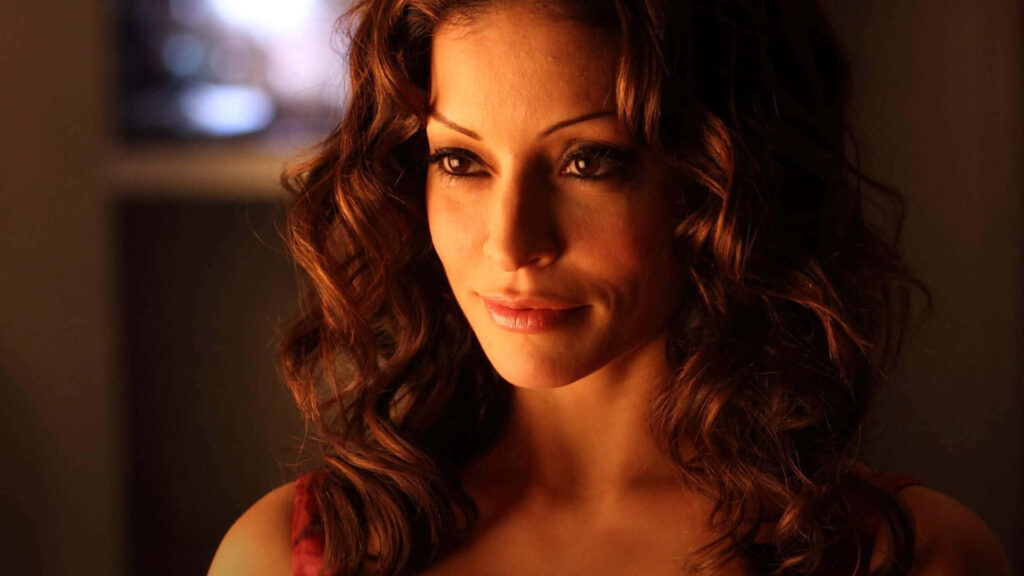 Close-up portrait of Emmanuelle Vaugier with warm lighting and wavy brown hair wallpaper background