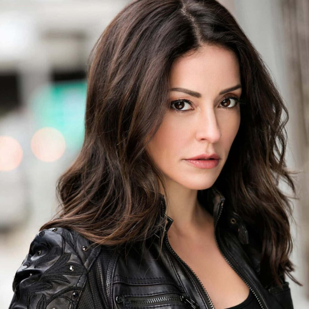 Emmanuelle Vaugier high resolution portrait with wavy dark hair and black leather jacket urban background Wallpaper