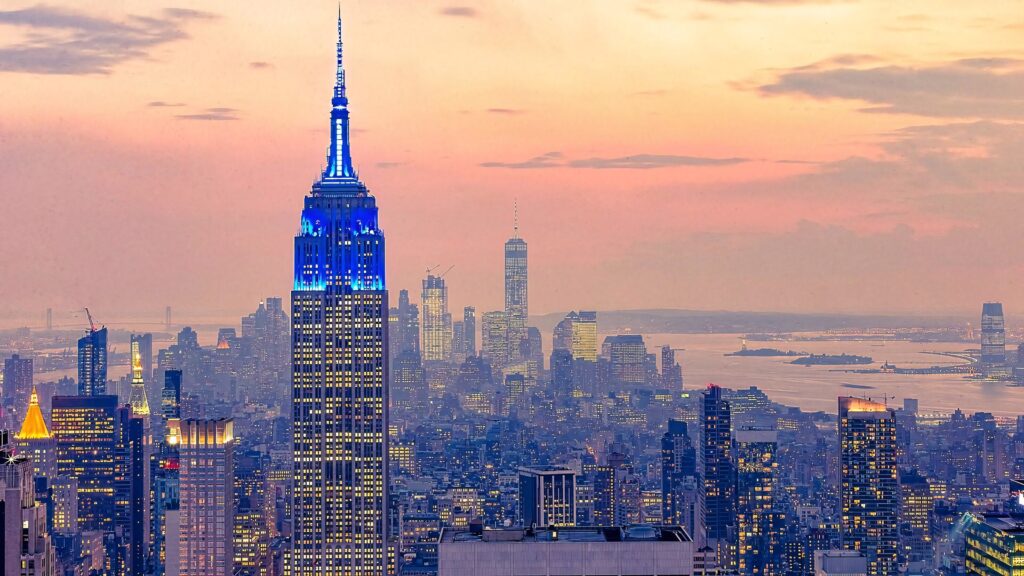 Empire State Building glowing blue at sunset with NYC skyline pastel sky high resolution wallpaper
