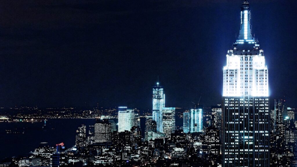 Empire State Building glowing blue white at night with vibrant NYC skyline cityscape wallpaper