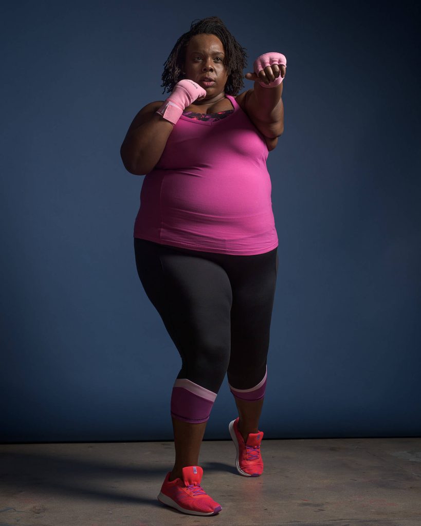 Plus-size woman with locs in pink wraps boxing pose strong confident fitness wallpaper background