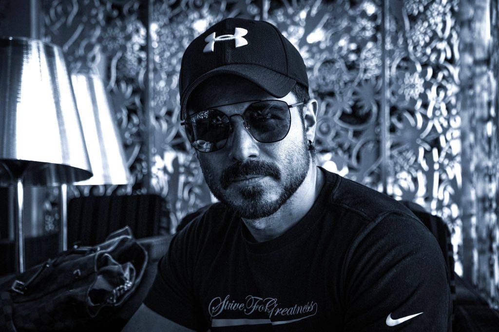 Emraan Hashmi black and white wallpaper wearing Under Armour cap sunglasses and Strive For Greatness tee