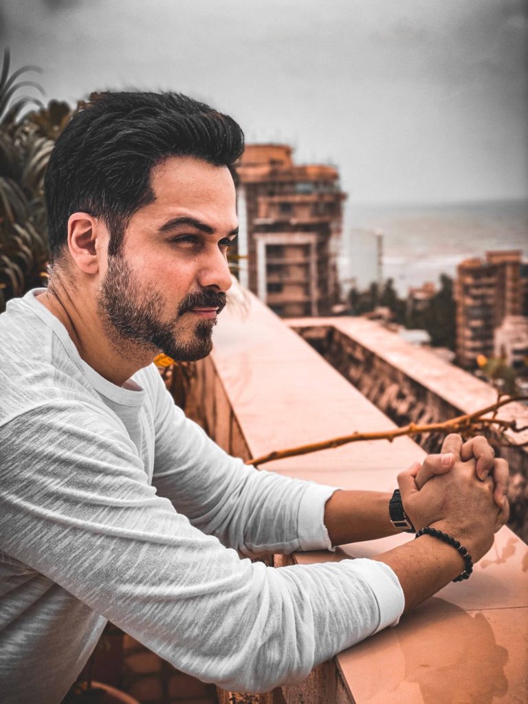 Emraan Hashmi profile portrait leaning on balcony railing in white shirt cityscape background wallpaper