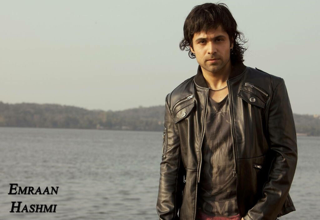Emraan Hashmi in black leather jacket by calm ocean with distant shoreline natural sunlit portrait Wallpaper