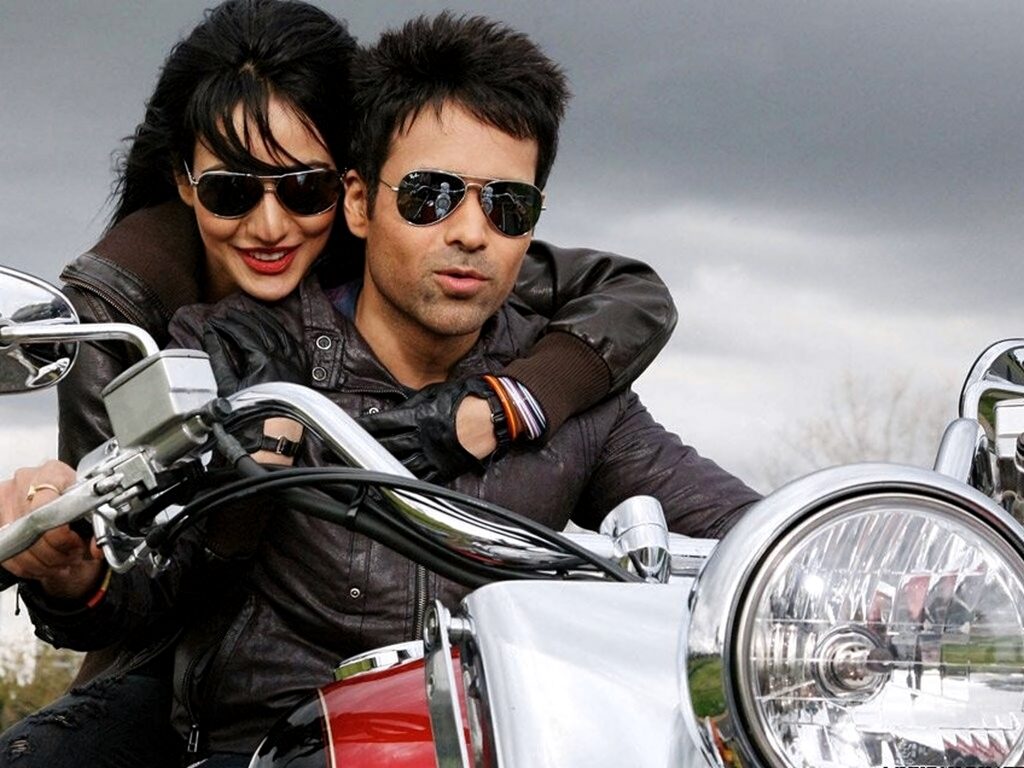 Emraan Hashmi and Neha Sharma riding motorcycle in leather jackets under cloudy sky from Crook film Wallpaper