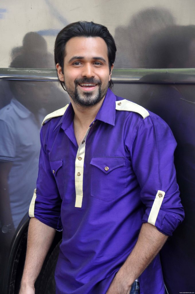 Emraan Hashmi smiling in vibrant purple shirt natural light dark reflective background wallpaper