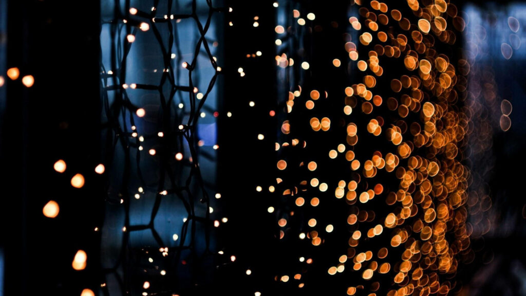 HD wallpaper of yellow Christmas lights with intricate strings and golden bokeh background