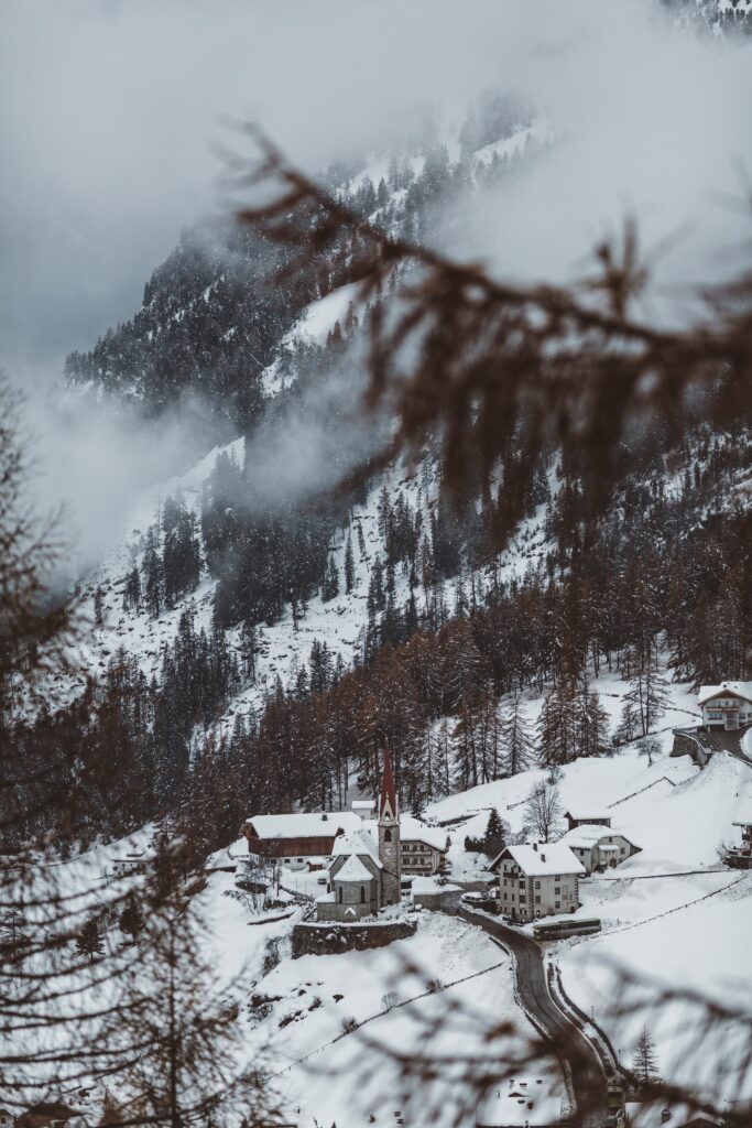 Aerial view of snow-covered mountain village with rustic buildings and pine trees in winter Wallpaper