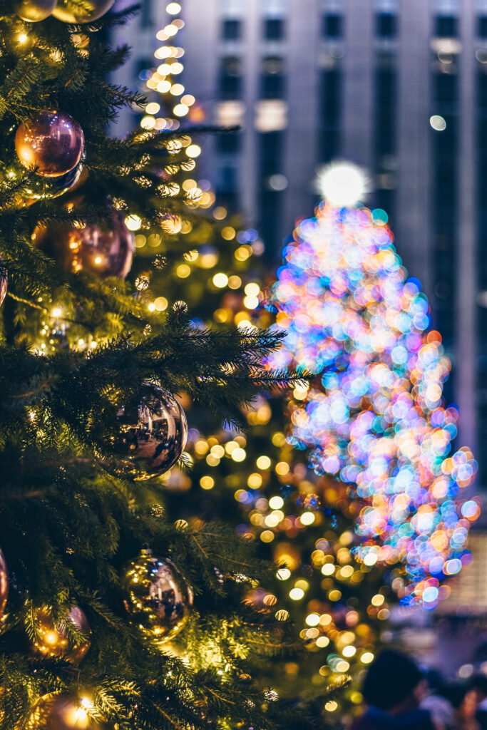 Enchanting Festive Foliage: Radiant Christmas Tree Adorned with Golden Ornaments Amidst Kaleidoscopic Backdrop Wallpaper