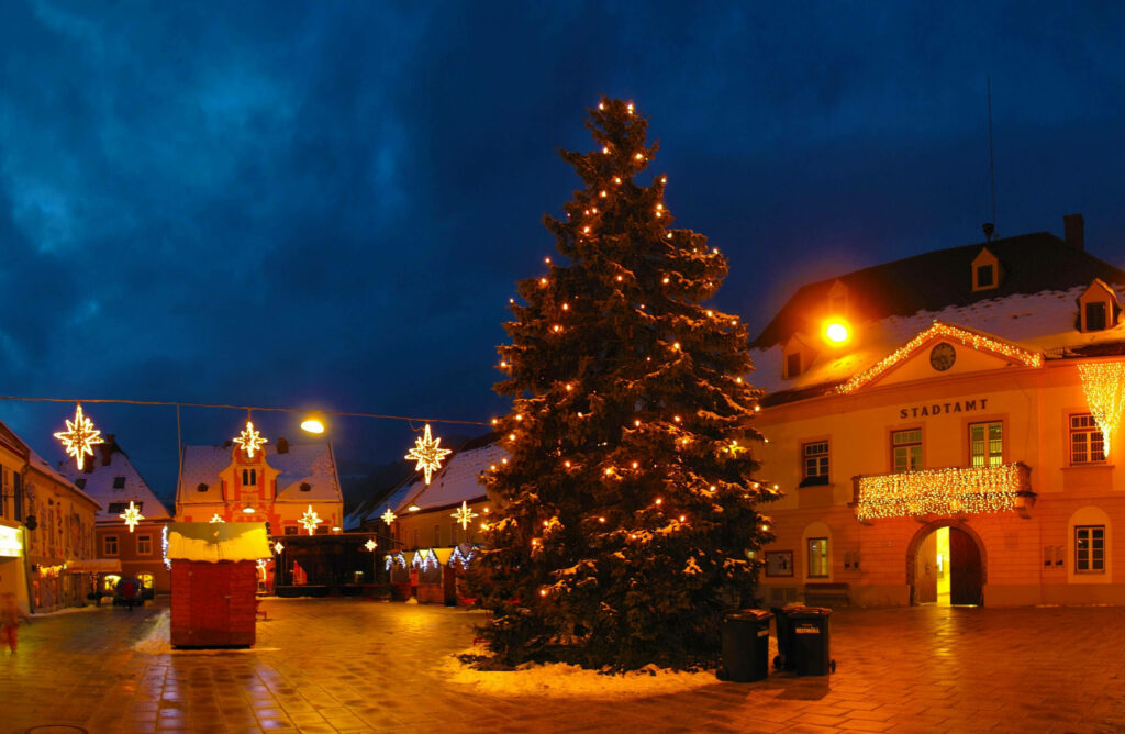 Cozy Christmas tree with warm lights in historic European square festive winter wallpaper