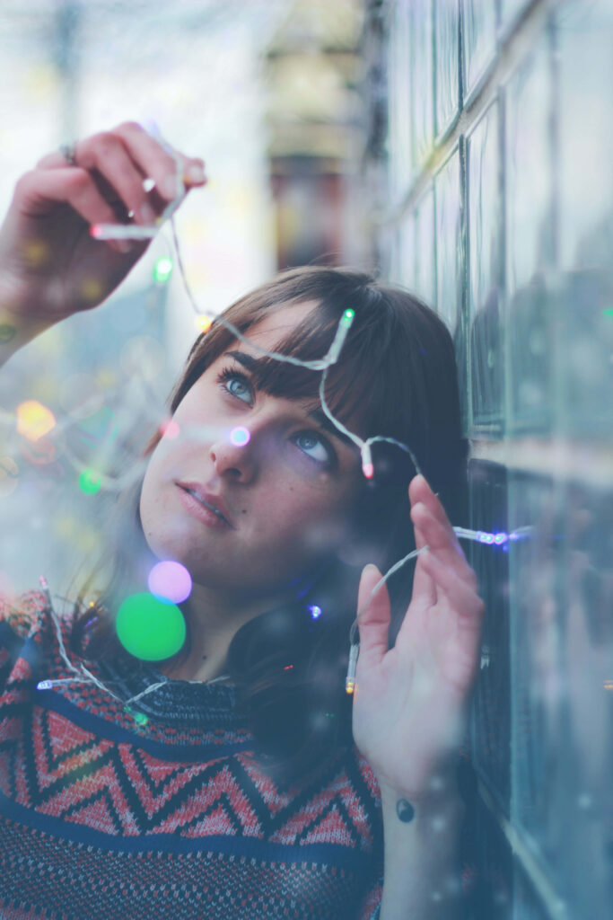 Enchanting Christmas Scene: Woman with Colorful Festive Lights Wallpaper