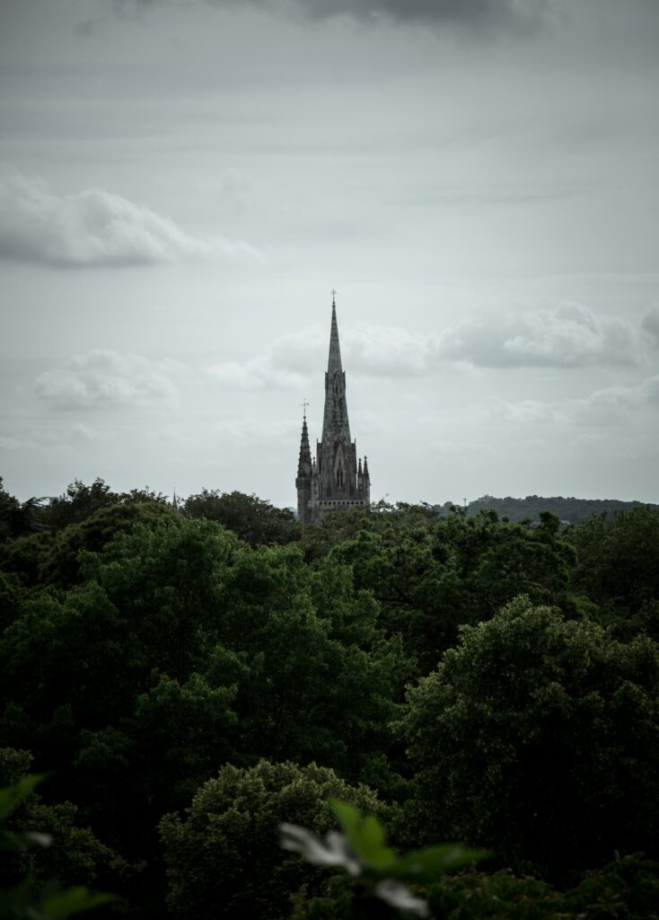 Enchanting Gothic Castle Spire Wallpaper Over Lush Green Canopy