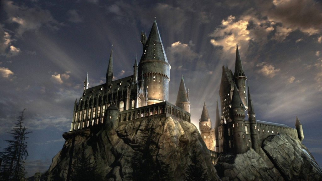 Hogwarts Castle glowing at dusk on cliff cinematic CGI Harry Potter magical wallpaper background