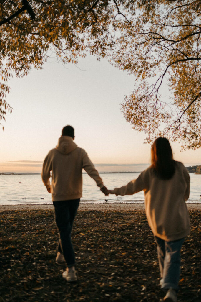 Enchanting Beachside Romance: Brown-Jacketed Couple Embracing Love on a Mesmerizing Full HD Wallpaper