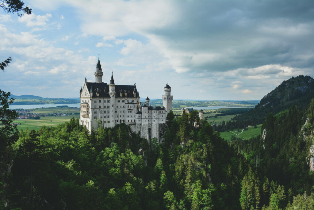Enchanting Neuschwanstein Castle Wallpaper Amidst Lush Greenery