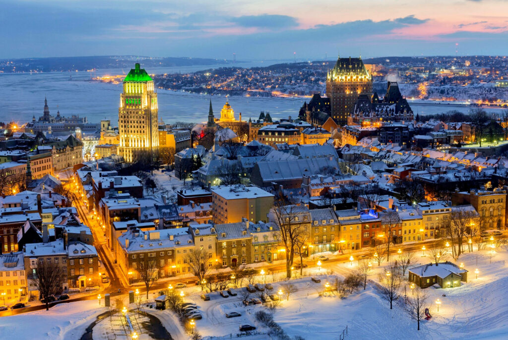 Old Quebec winter night with snow-covered Château Frontenac and glowing city lights skyline Wallpaper